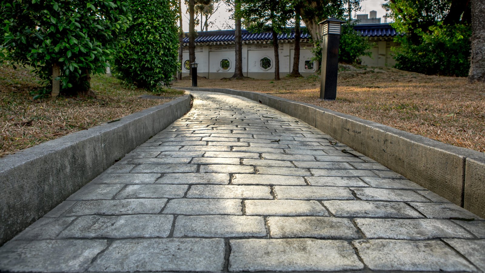 Landscaping with a curved stone paver walkway, concrete edging, and lawn with trees in the San Fernando Valley